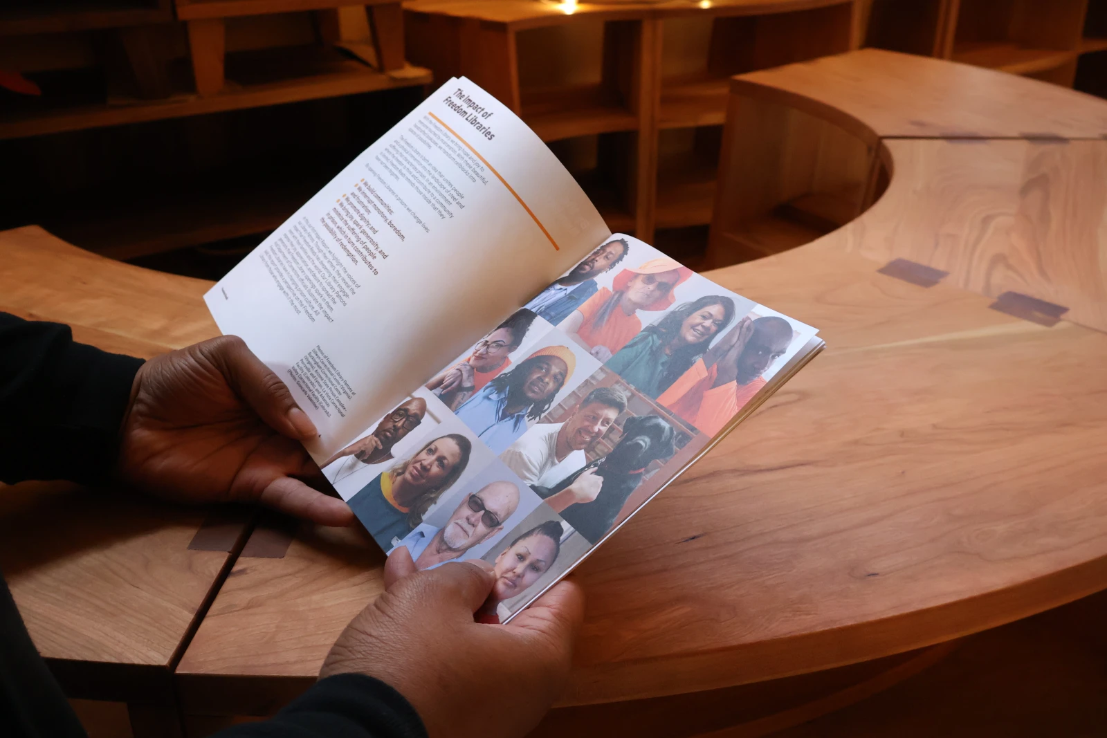 Hands holding the Freedom Reads Impact Report in front of a Freedom Library bookcase.