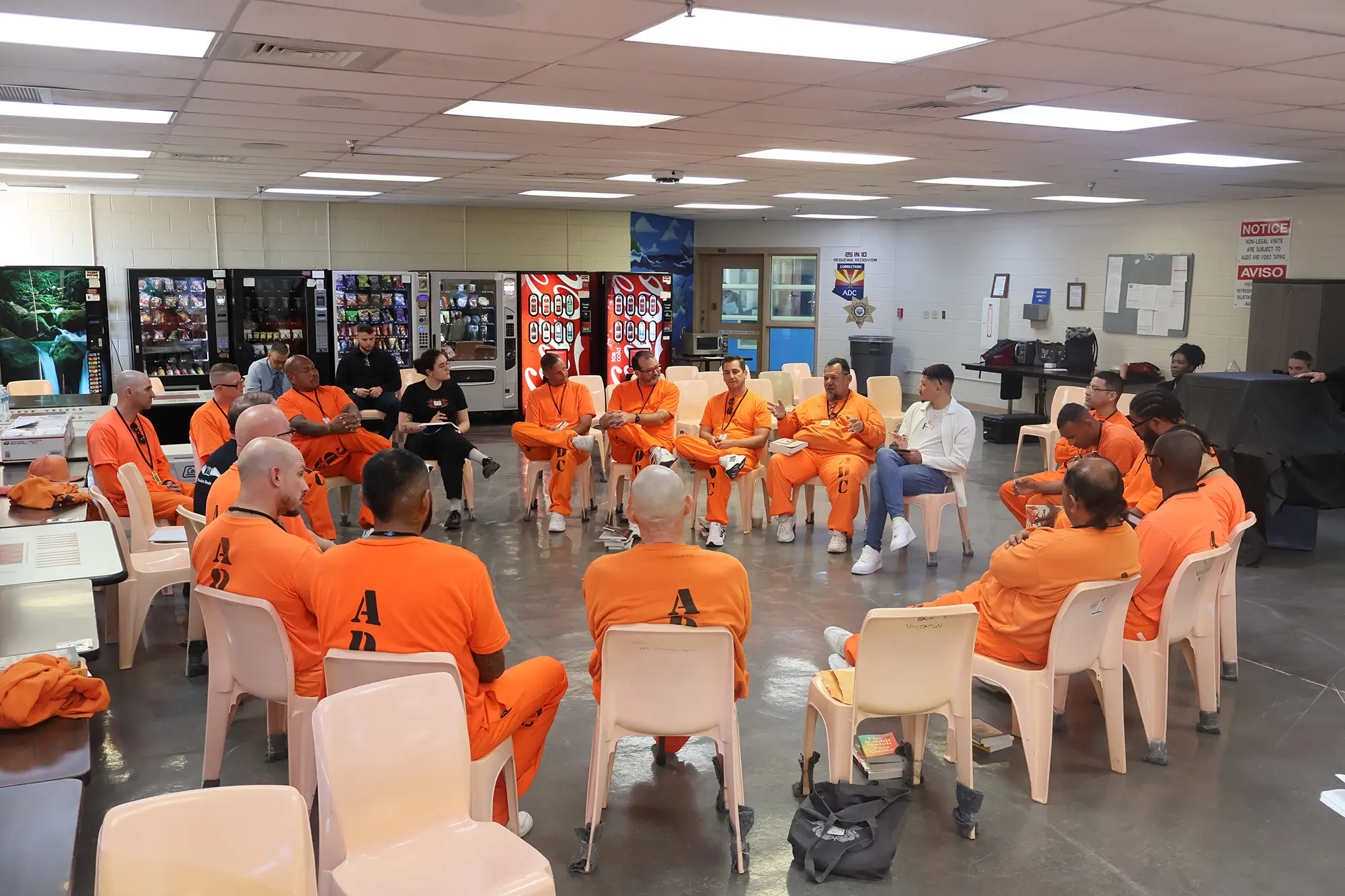 Men clad in orange seated in a circle discussing books inside Arizona State Prison Complex - Eyman.