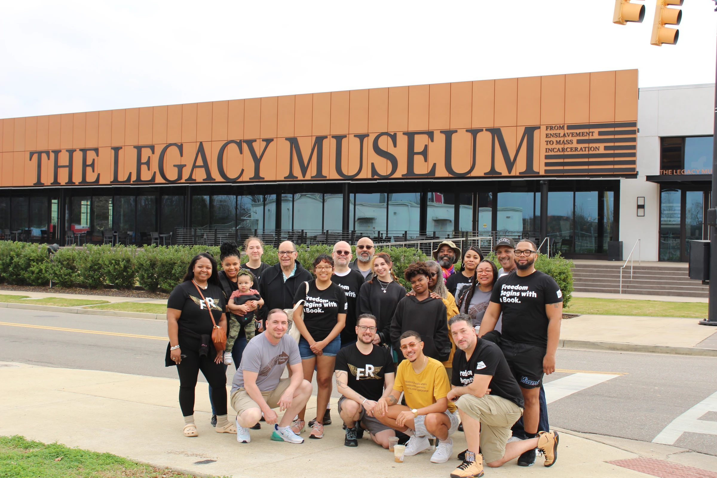 The Freedom Reads team and guests pose for a group photo outside of the Legacy Museum in Montgomery, Alabama. Many people wear Freedom Reads t-shirts that say, Freedom begins with a book.