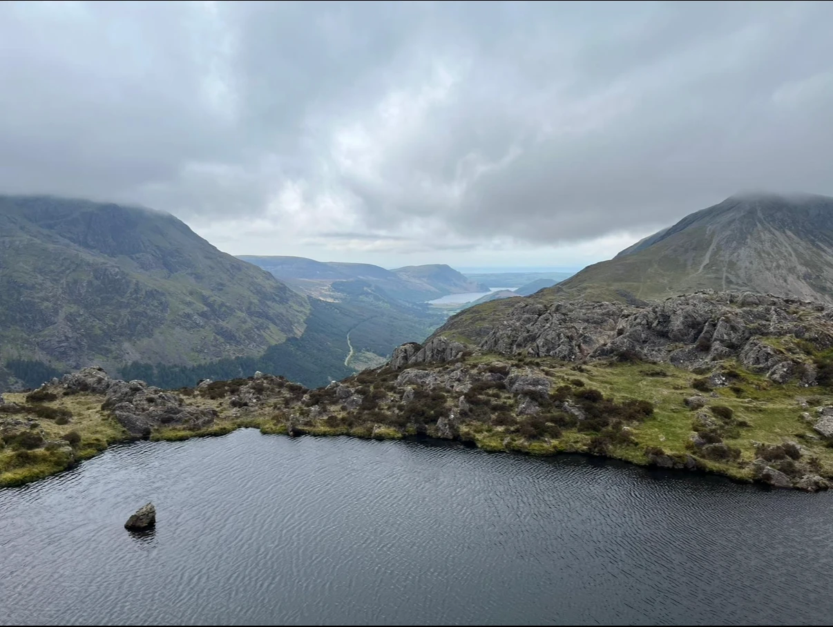 Picture of a beautiful lake with mountains on two sides, all under a storm cloud filled sky.