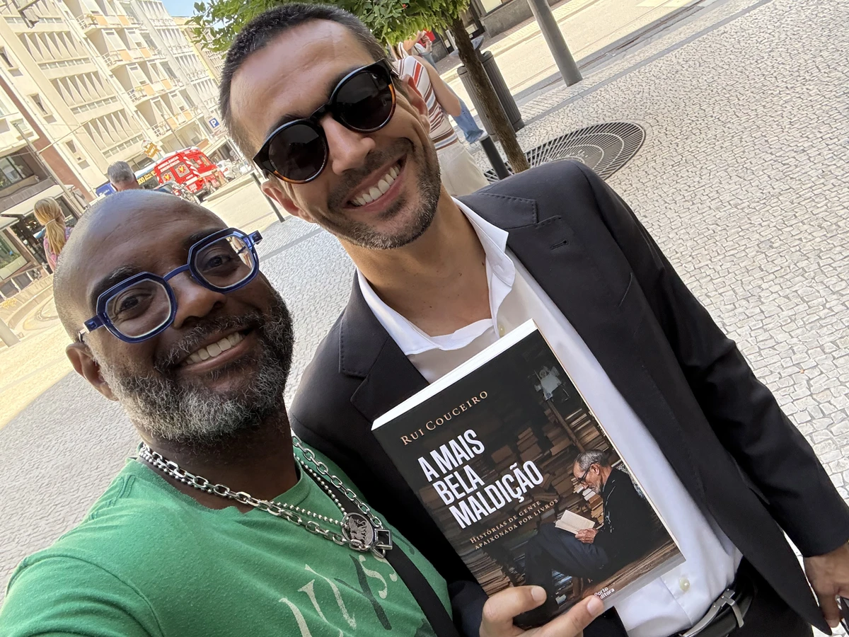 Two men taking a selfie while holding a book.