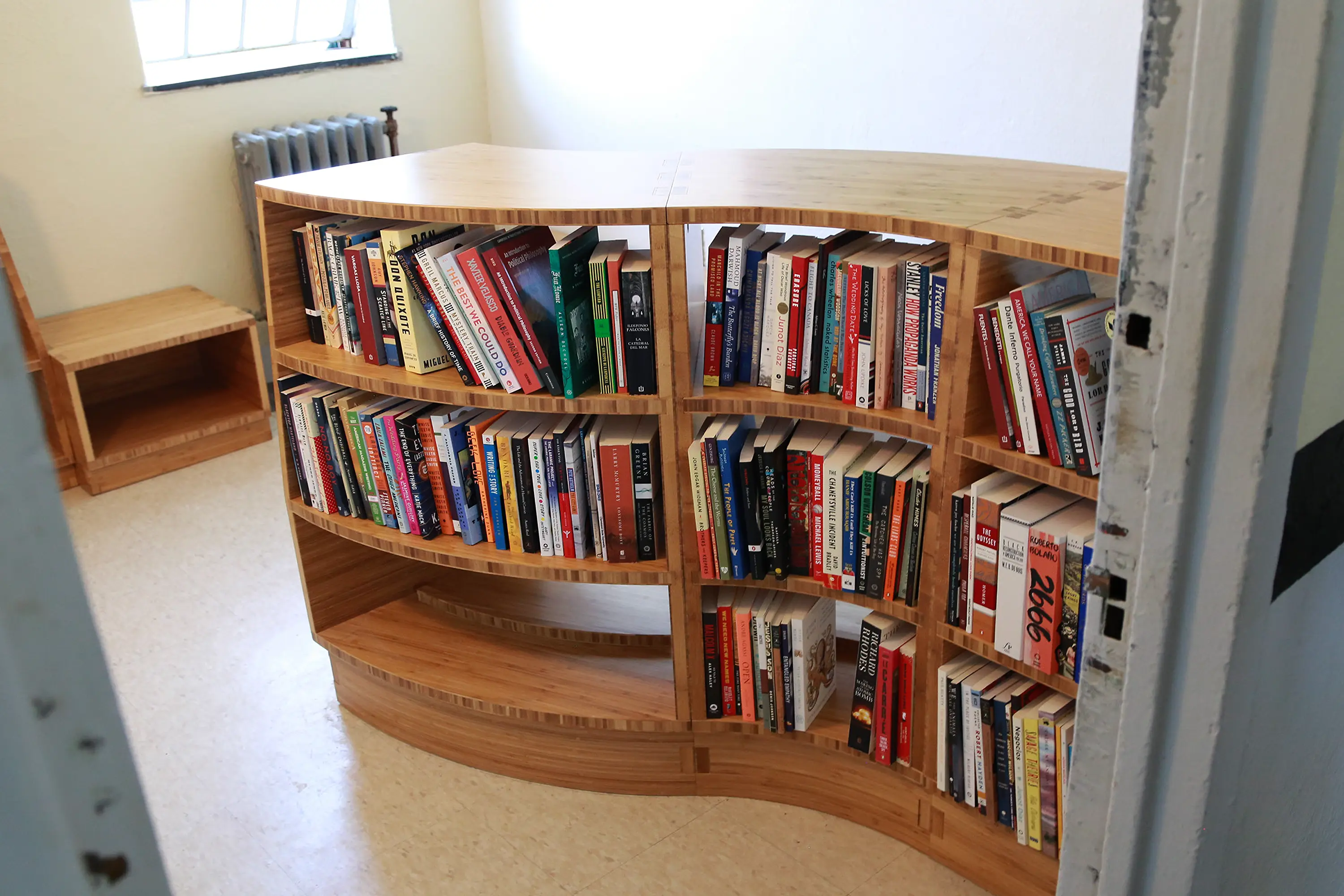 Room with a wooden Freedom Library bookcase made of three curved modules filled with books.