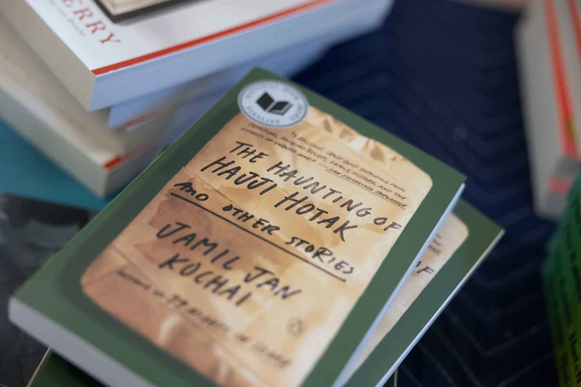 A closeup photo of book cover with handwriting on brown packaging for The Haunting of Hajji Hotak and Other Stories by Jamil Jan Kochai