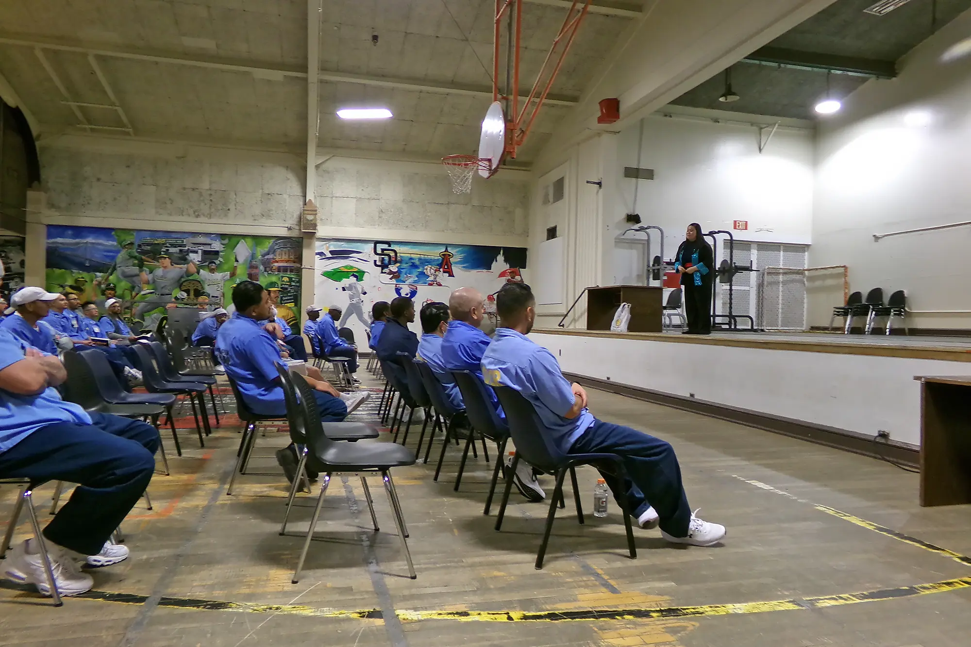 Gaosong Heu performs in a gymnasium with seated men all clad in blue at Salinas Valley State Prison in California.