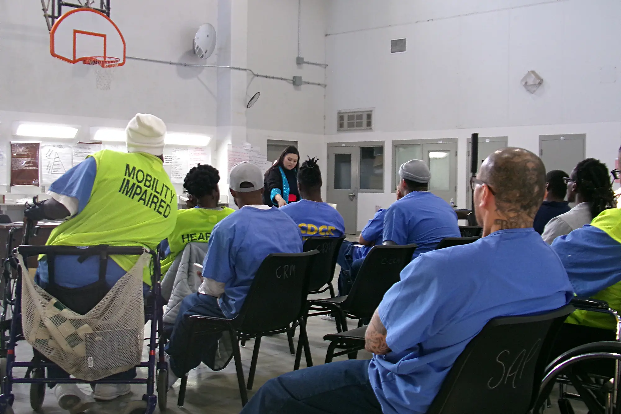 Gaosong Heu performs on a stage in front of a crowd of blue-clad men at Correctional Training Facility in California.