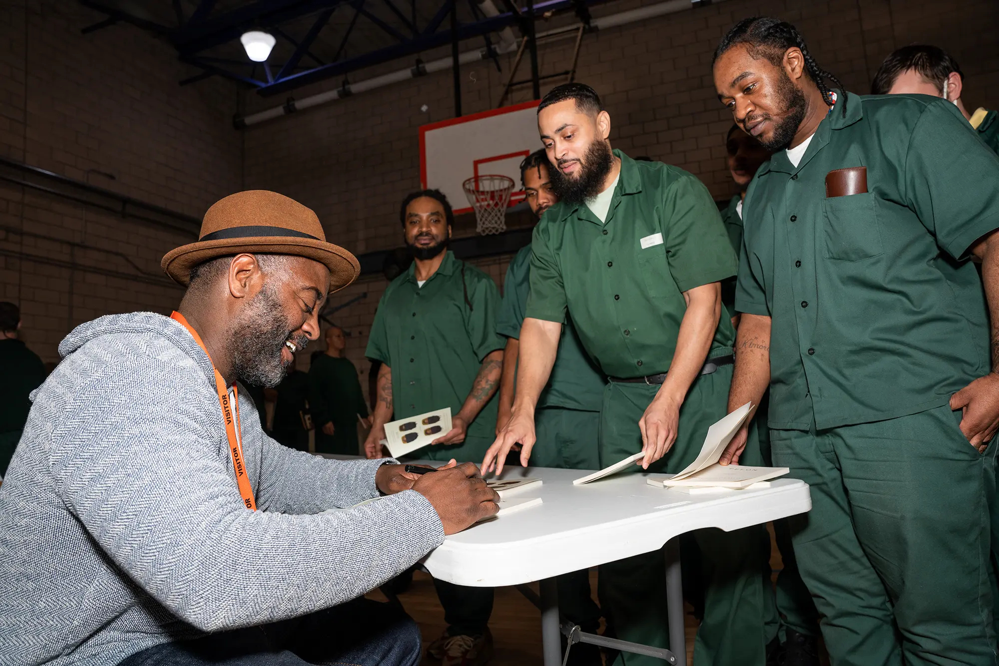 Reginald Dwayne Betts smiles while signing copies of his book, FELON, for men lining up to meet him at Woodbourne Correctional Facility in New York.