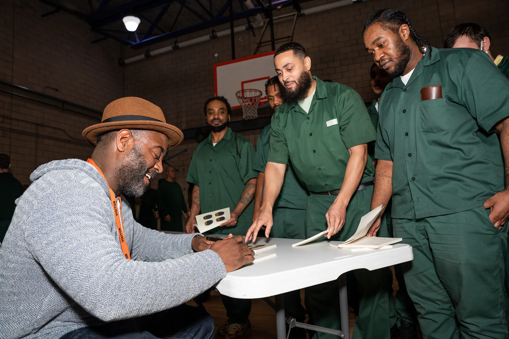 Men gather around a table awaiting Freedom Reads Founder & CEO Reginald Dwayne Betts to sign their copies of FELON after a reading at Woodbourne Correctional Facility in New York.